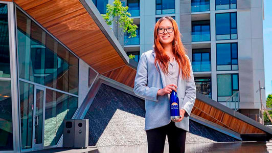 A student stands in front of a building holding a Parks Canada water bottle.