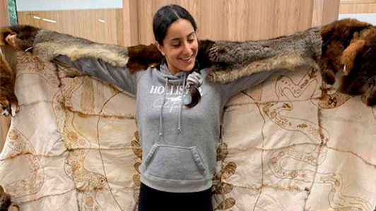 A student wears a fur cloak that includes Indigenous stories.