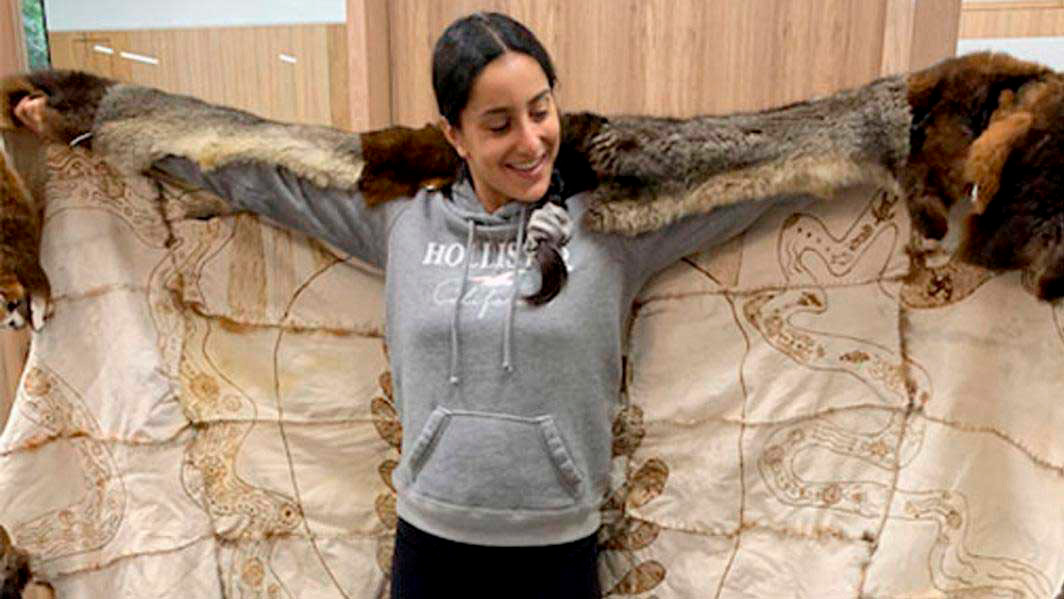 A student wears a fur cloak that includes Indigenous stories.