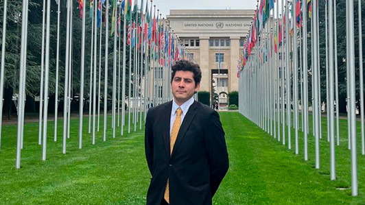 A man stands in front of flags from many different countries at the United Nations in Switzerland.
