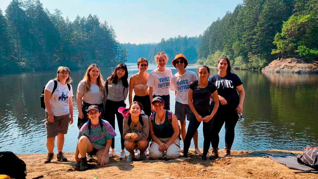 A group of people stand in front of a lake.