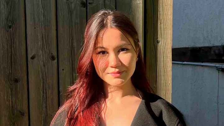 A student with long hair smiles at the camera.