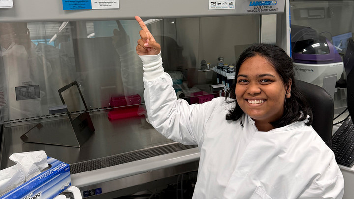 A student wearing a lab coat in a lab.
