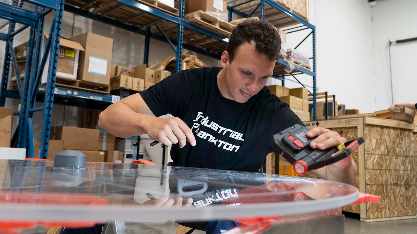 A man adjusts a piece of equipment in a warehouse.