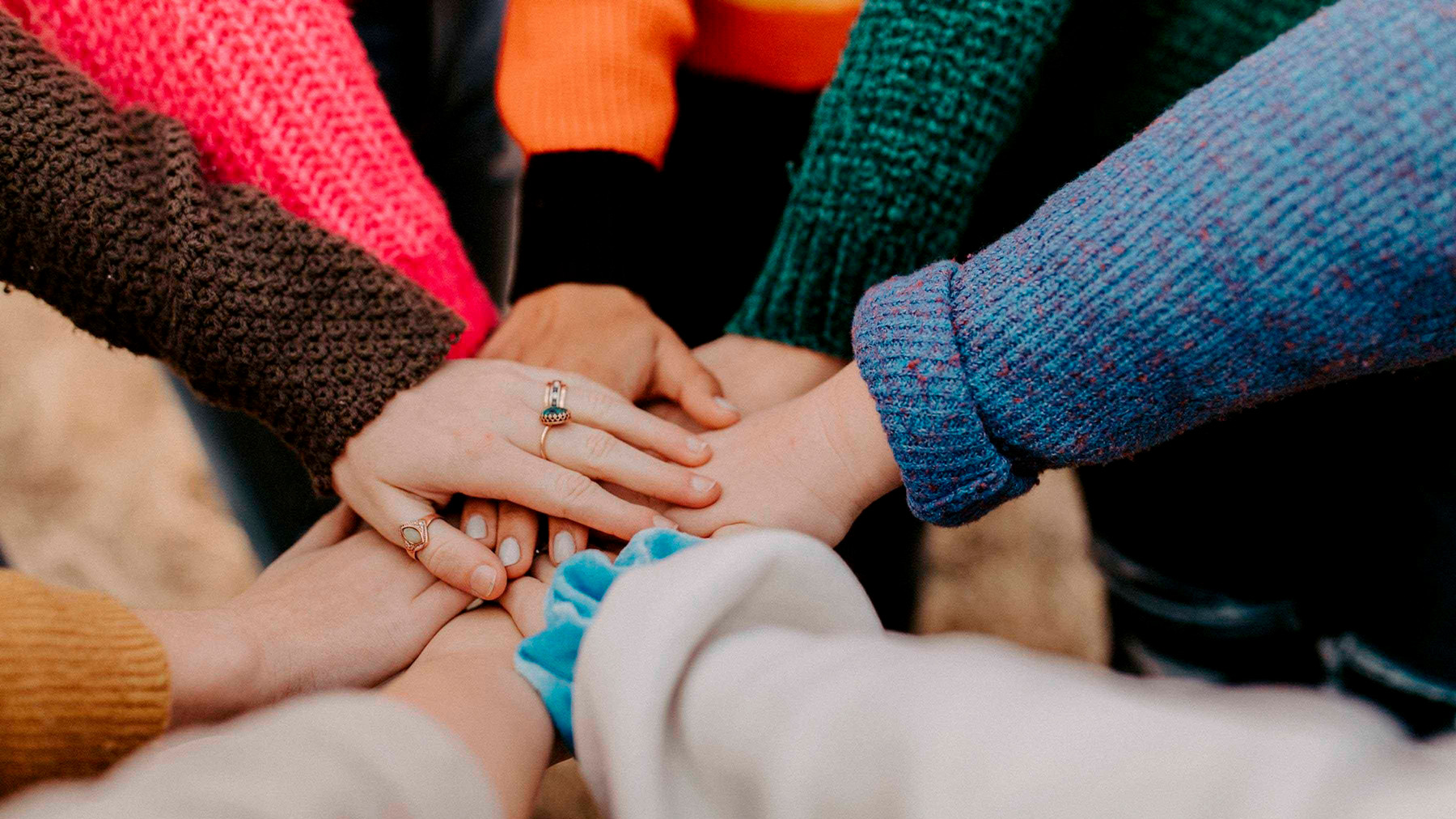 Several hands come together in a circle.