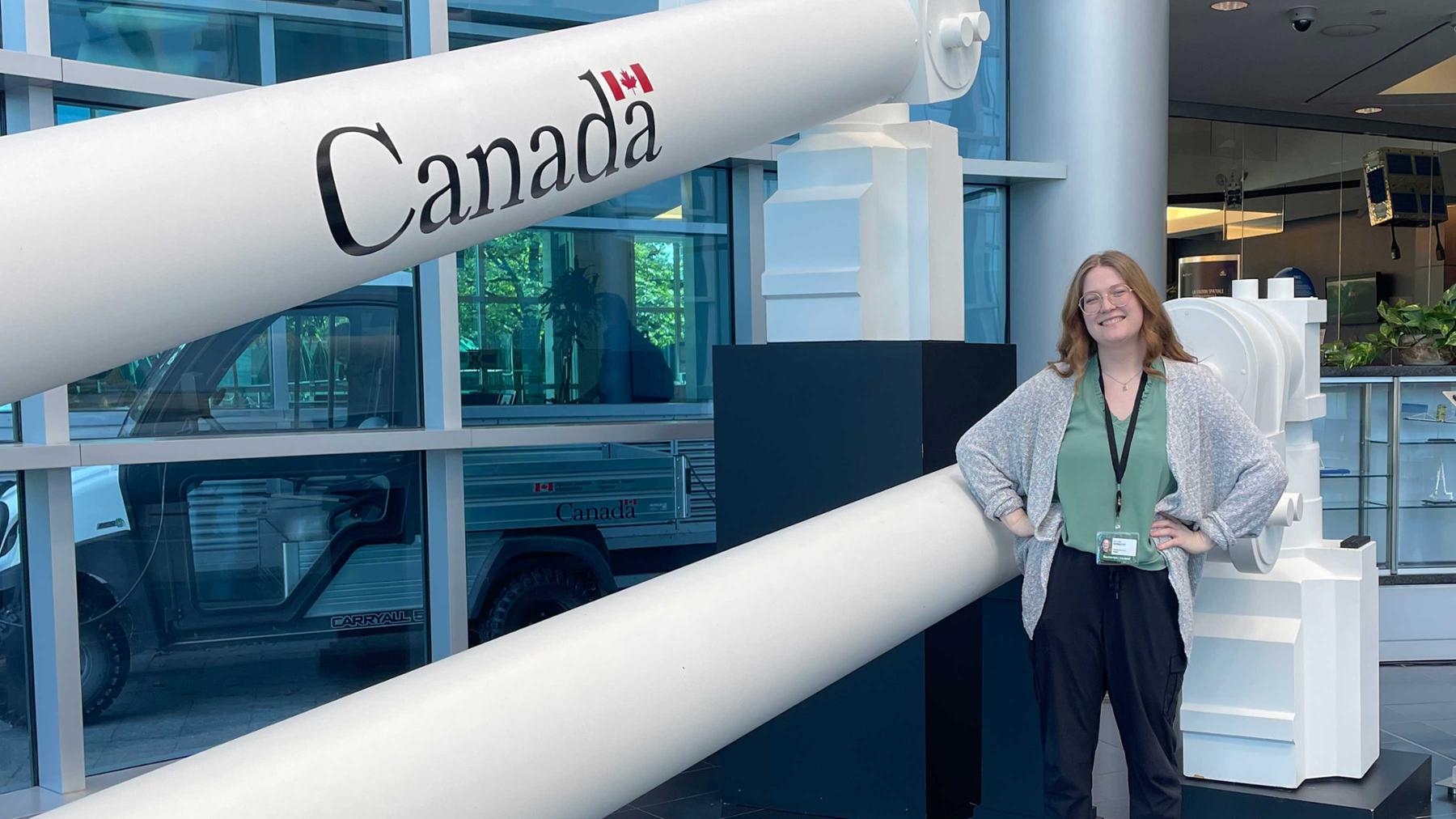 A student stands in front of a model rocket at the Canadian Space Agency
