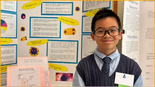 A young student stands in front of a poster board presentation at a science fair.