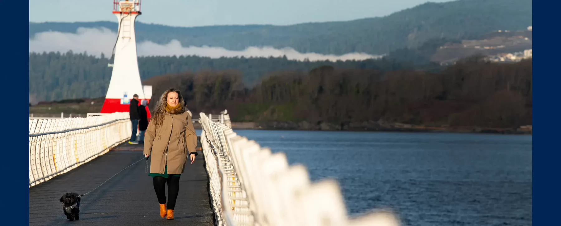 A woman walks her dog along the Victoria breakwater path.