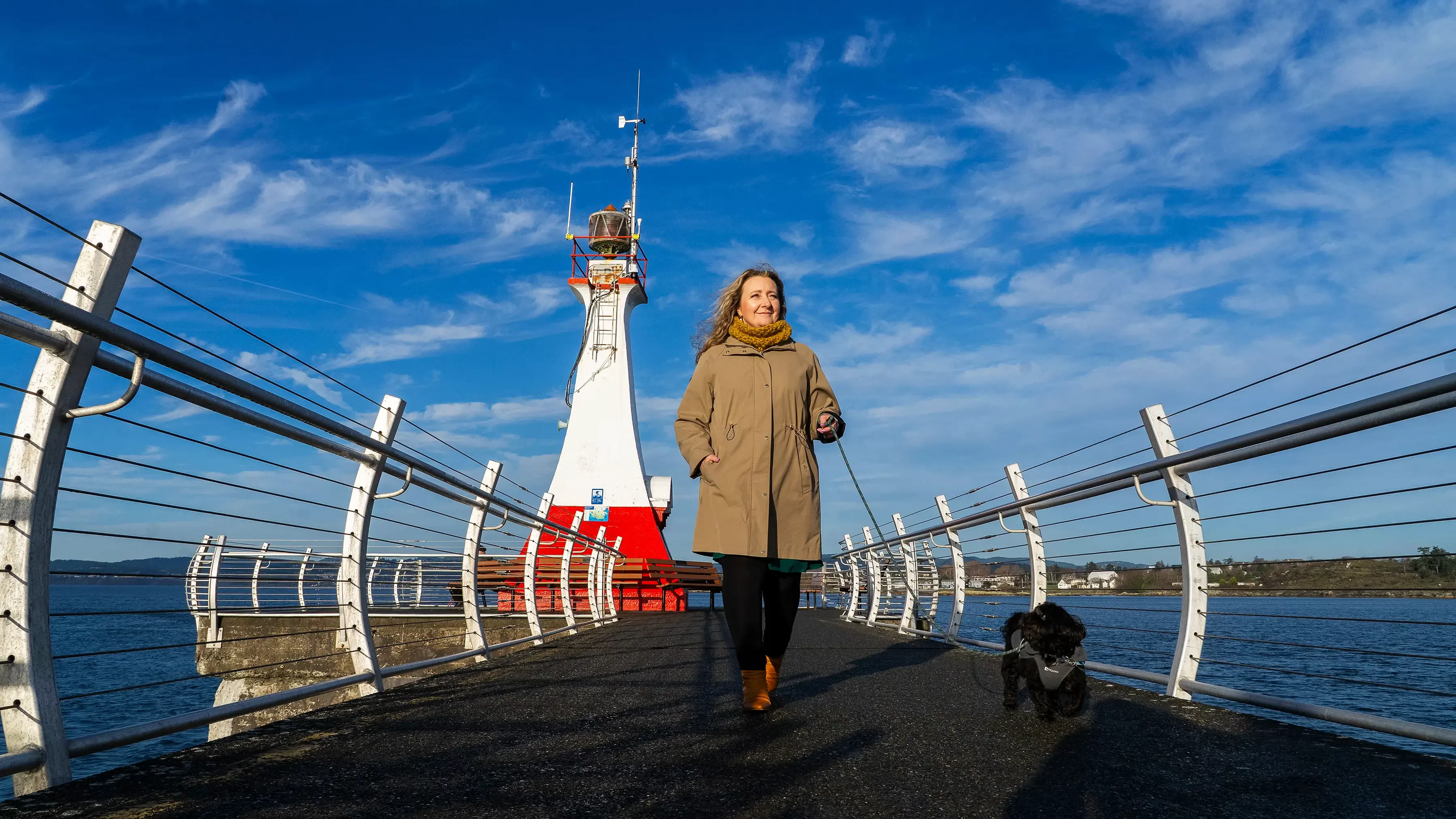 A woman walks her dog along the breakwater path in Victoria.
