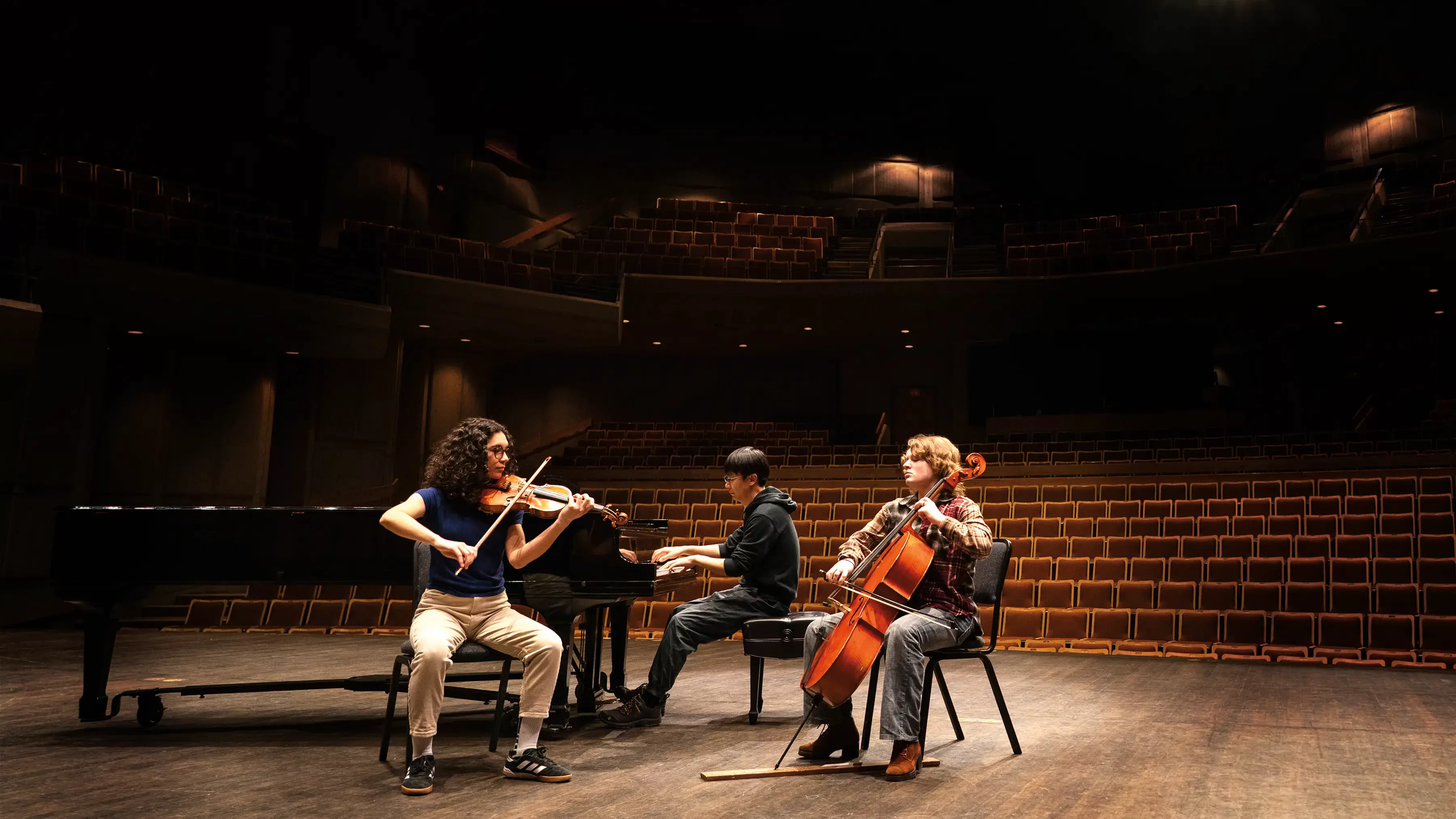 A trip of students in a concert hall playing instruments.