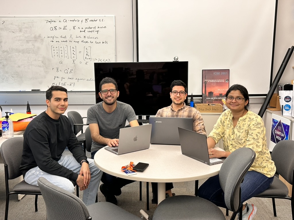 Four students sitting around a table with laptops.