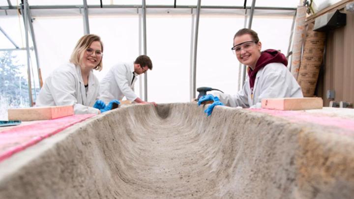 two students working on concrete canoe