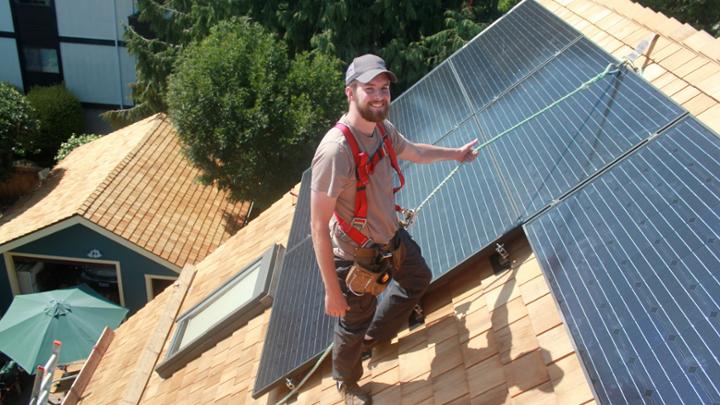 student on roof installing solar panels