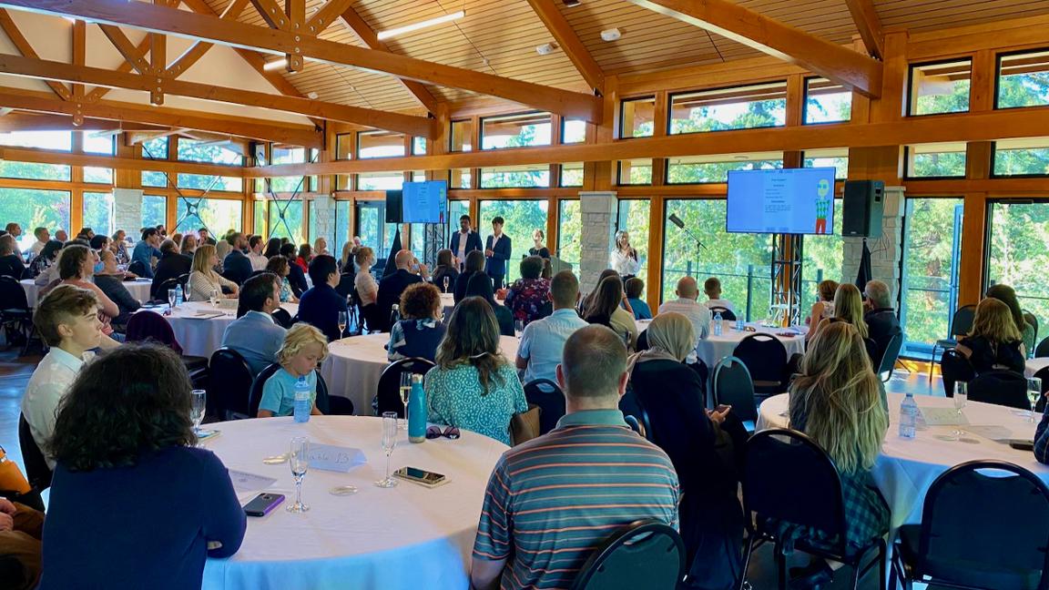 People watching a presentation while sitting at tables.