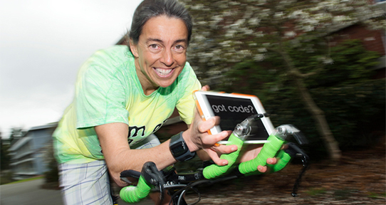 Yvonne Coady riding a bicycle and holding a computer