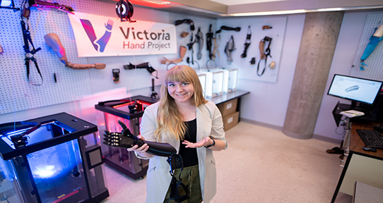 Kelly Knights holding a 3D-printed hand model in the Victoria Hand Project lab.