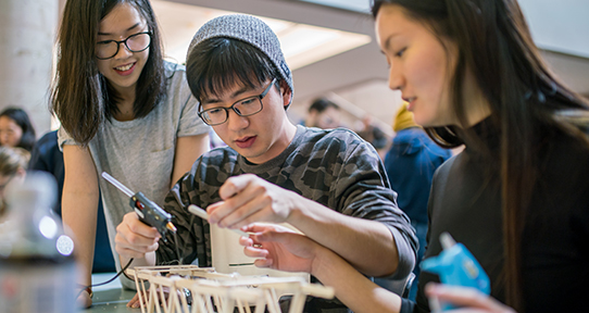 UVic students working on a Popsicle stick bridge together in a lab
