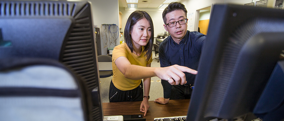 Amy Sun gestures to a computer screen with another person