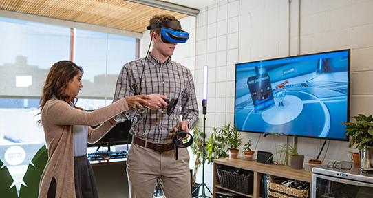 Tania Akter showing someone how to use a virtual reality set