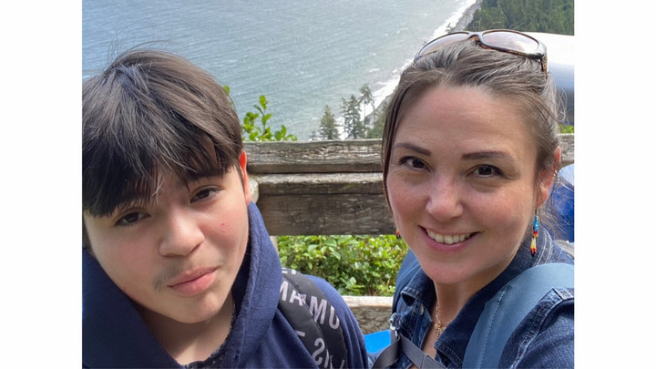 Corina and her son pose for a selfie on a hill overlooking the coastline.