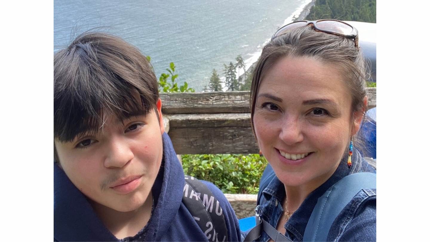 Corina and her son pose for a selfie on a hill overlooking the coastline.