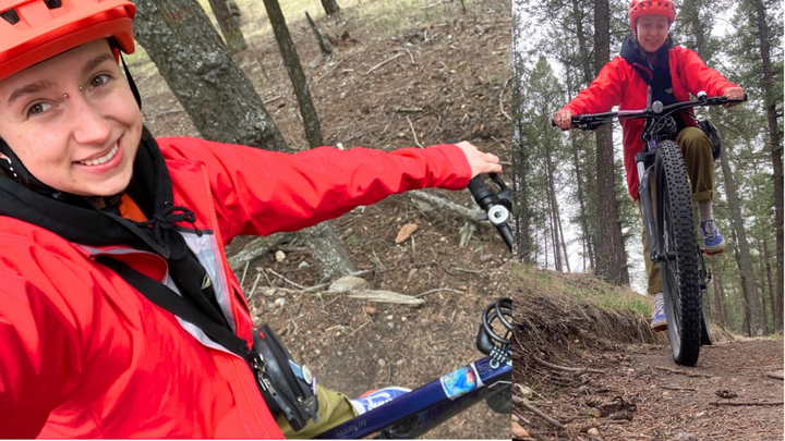 Graham is pictured having a great time on their bike riding on a forest trail to and from school. They are wearing a red rain jacket and a matching red helmet. 