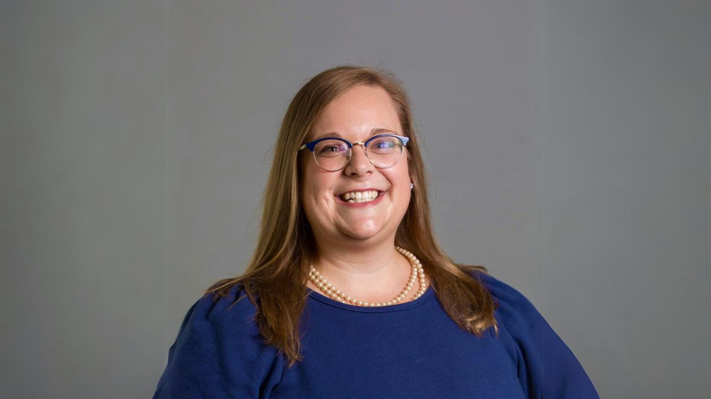A portrait of Dr. Sarah Nutter. She is smiling into the camera, wearing a cobalt blue top.