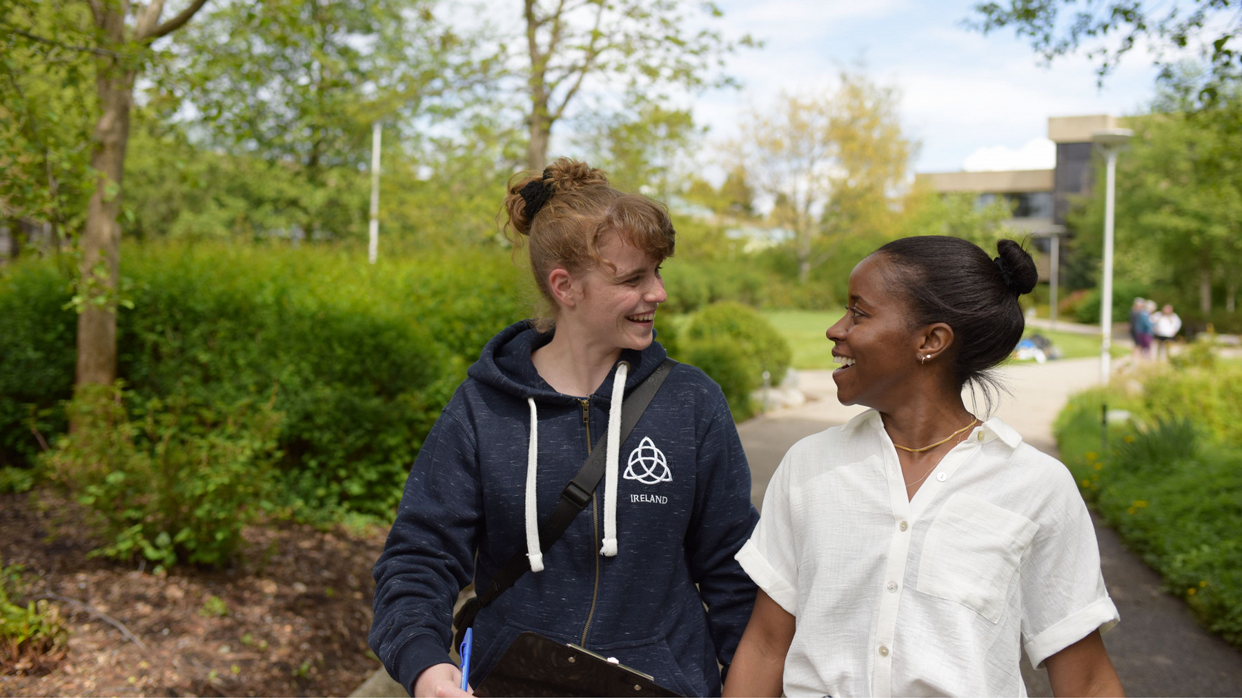 Two students pictured walking together on campus, engaged in conversation.