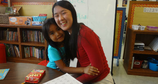 Tutor hugs a student while working on math at Kwum Kwum Lelum