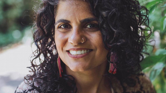 A closeup portrait of Mandeep Kaur Mucina. She is pictured outdoors, smiling.