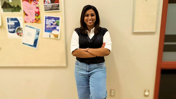 Chandrinaa Mohan smiling and leaning against a wall.