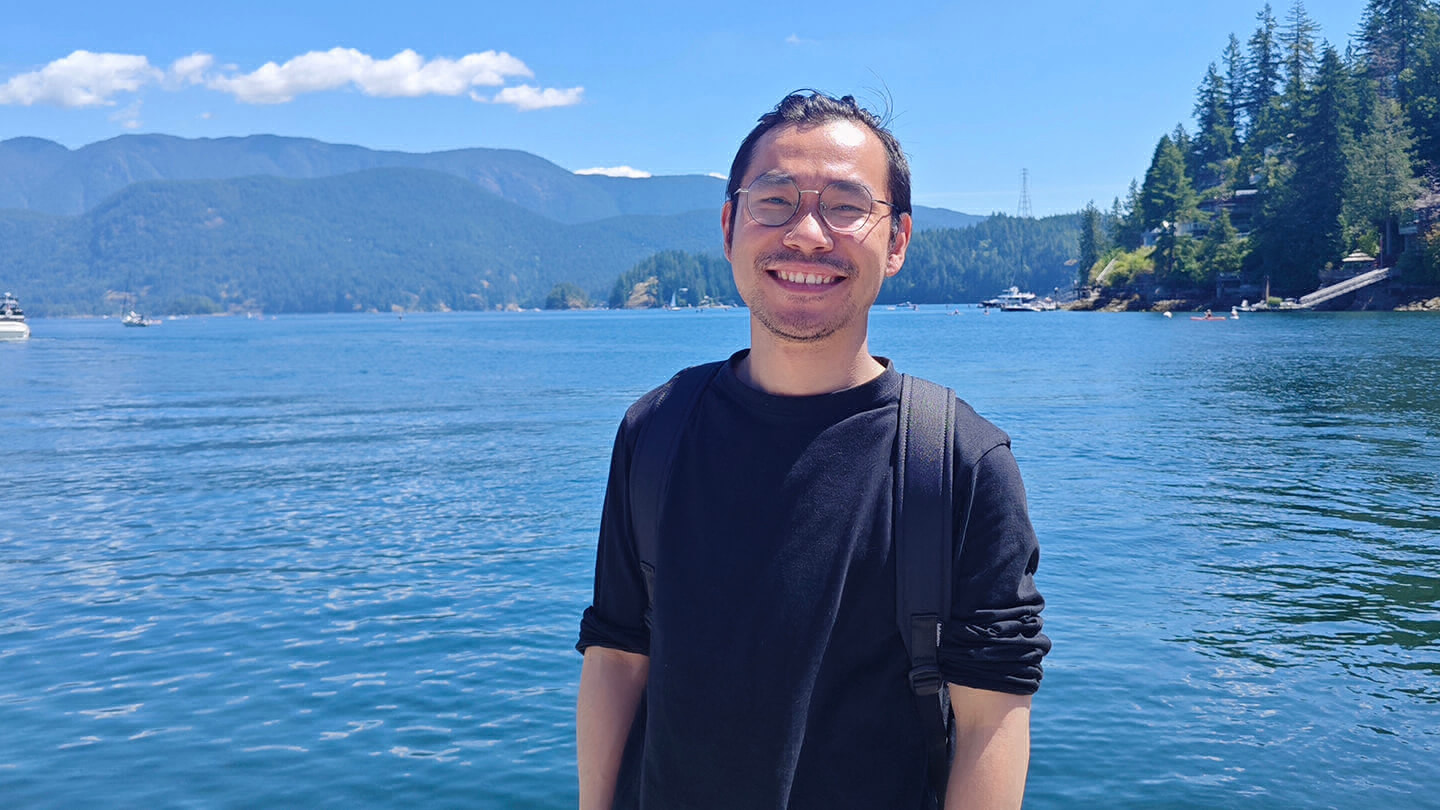 Travis Yang standing in front of the ocean on a sunny day.