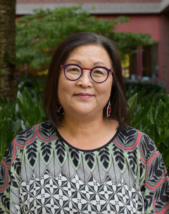 A head-and-shoulders portrait of Jin-Sun Yoon on campus. They are pictured outdoors, wearing a colourful patterned blouse and bold glasses.