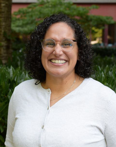 A head-and-shoulders portrait of Morgan Mowatt on campus. They are pictured outdoors, wearing a white sweater.