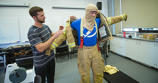 Cory Coehoorn helping a fire fighter put on gear