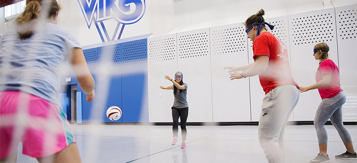 Blindfolded students playing soccer in the UVic gym