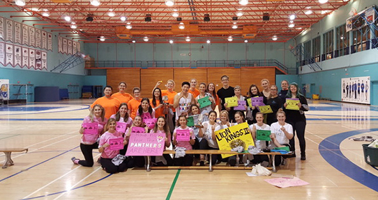 A group of students in the UVic gym holding posters