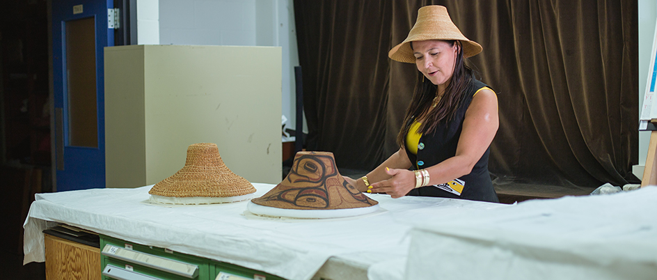 Alumna Lucy Bell looking at Haida hats in a museum
