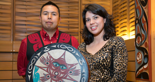 Two Indigenous people holding a ceremonial drums