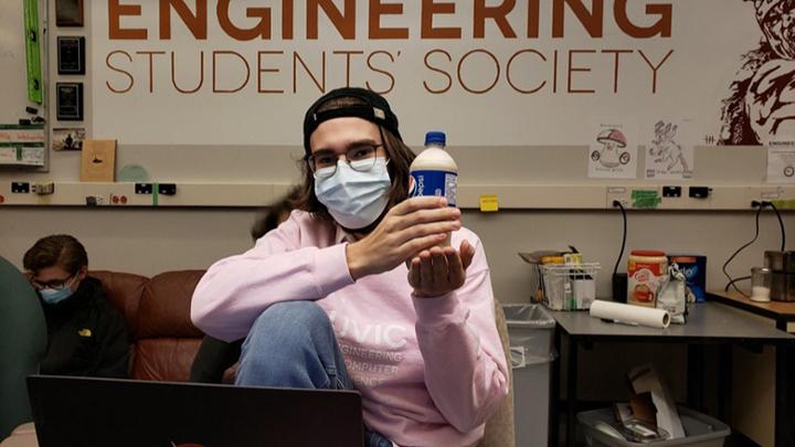 student holding plastic pop bottle