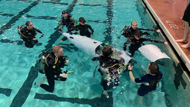 group of students in pool with submarine