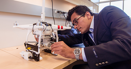 graduate student examining drone that is sitting on a desk