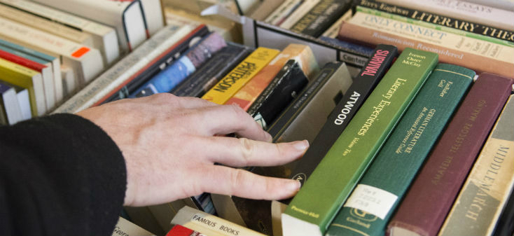 A person's hand choosing from a selection of books.