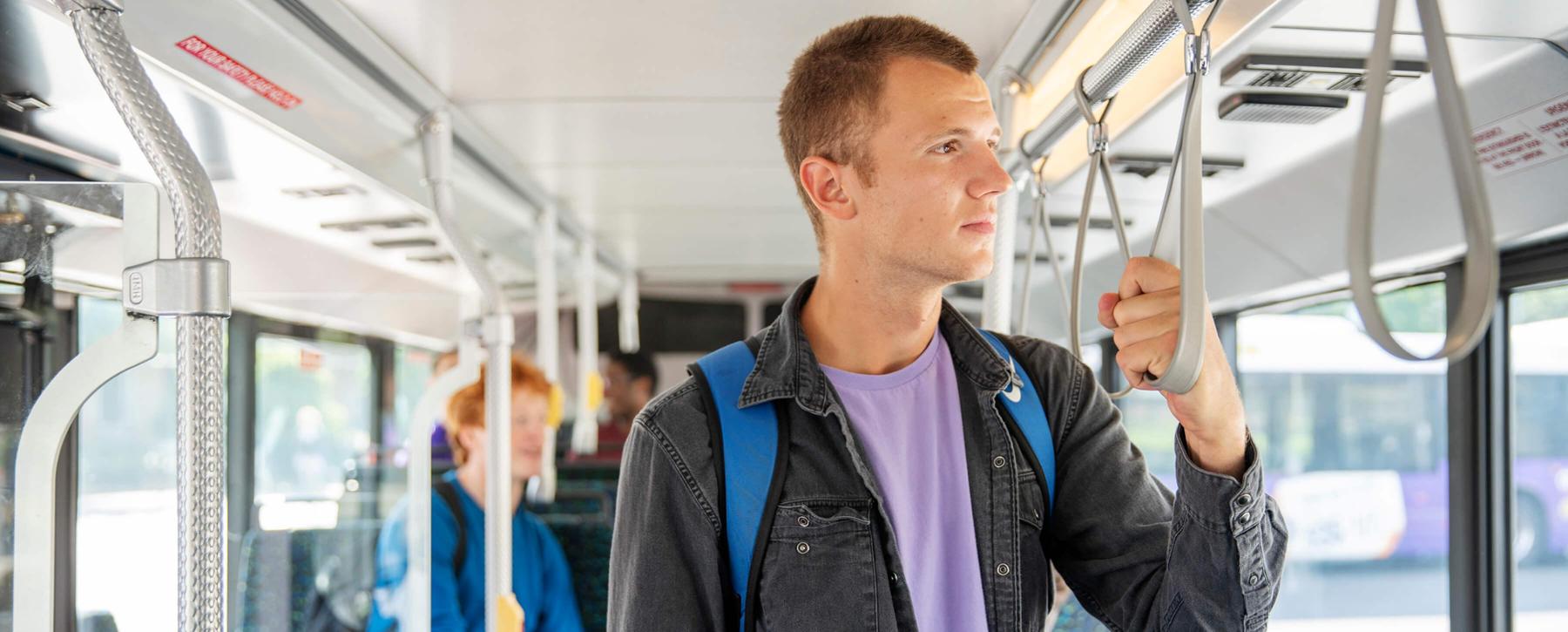 A person holds a hand strap while riding a bus.