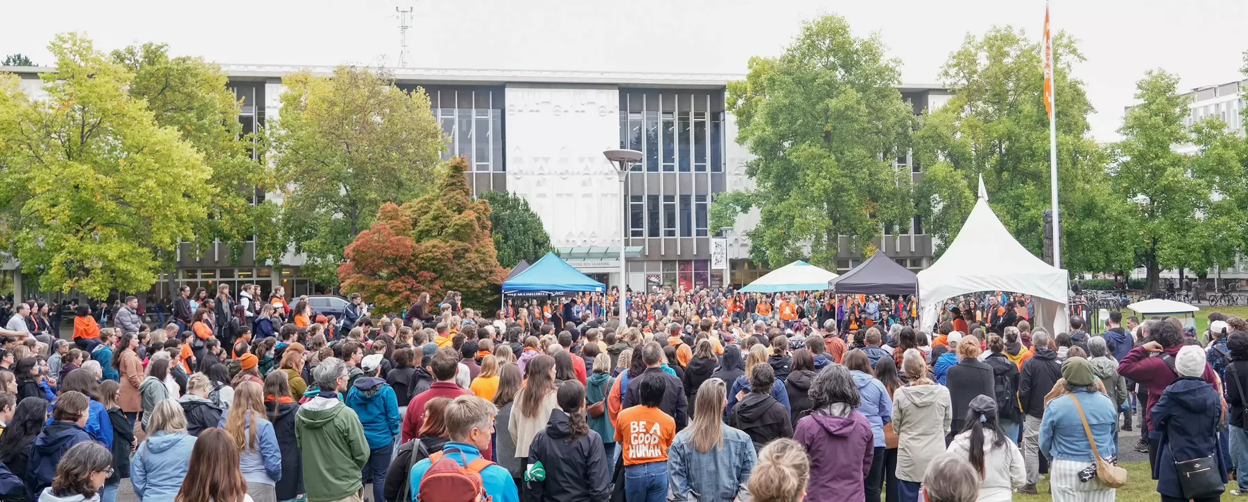 A large crowd of people attend the Orange Shirt Day ceremony on campus.