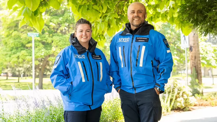A man and a woman in blue campus security jackets standing outside.