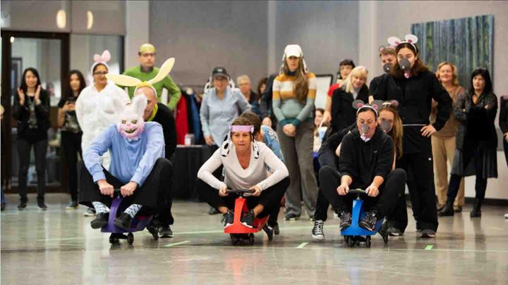 Four UVic employees wearing costumes race plasma cars across a room.