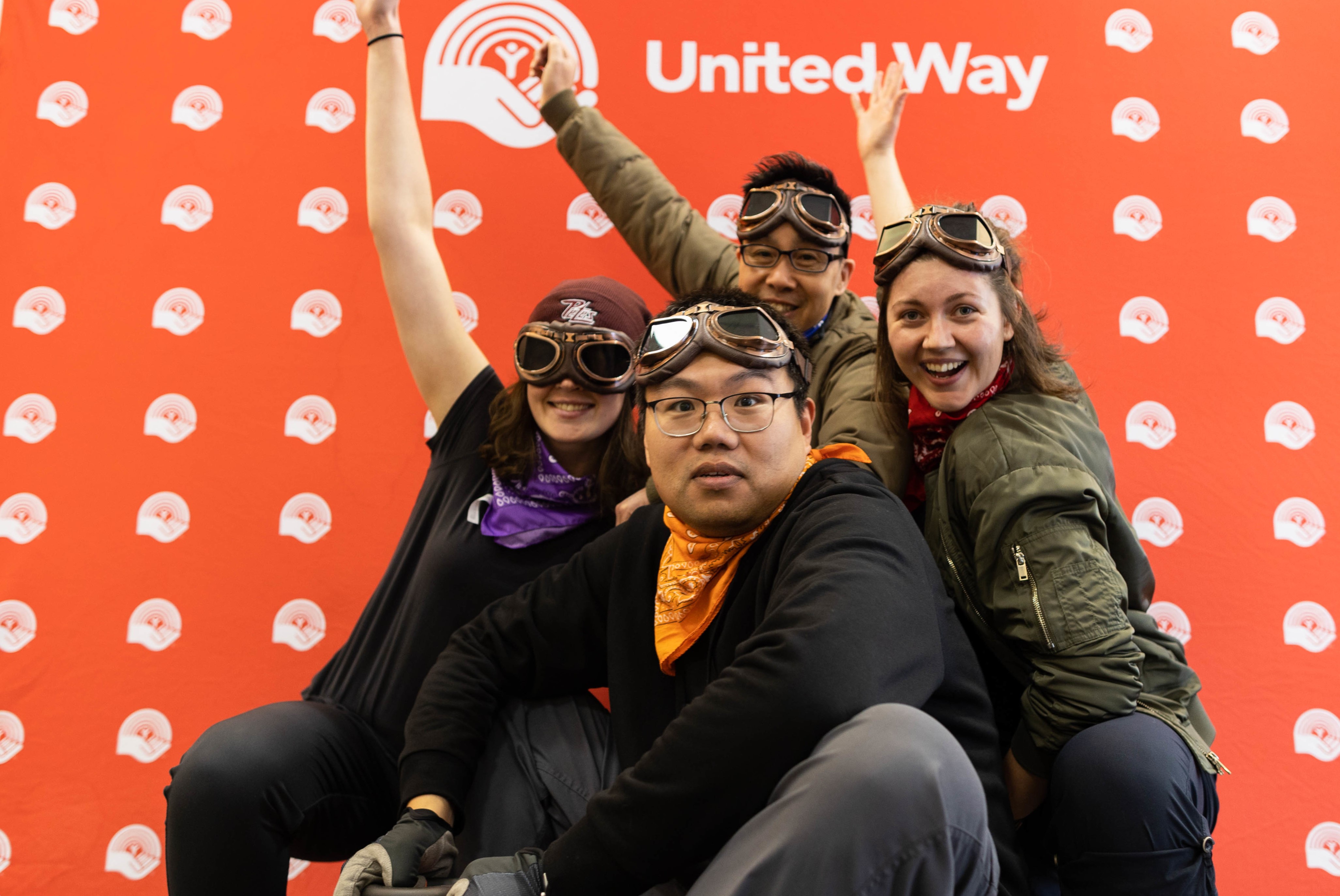 Four people crouching in front of a united way background in costume