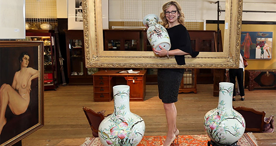 Alison Ross holding a vase and standing in a large photo frame