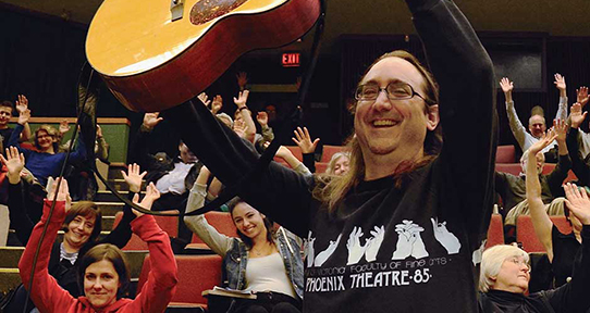  Mark Leiren-Young holding up a guitar during a lecture